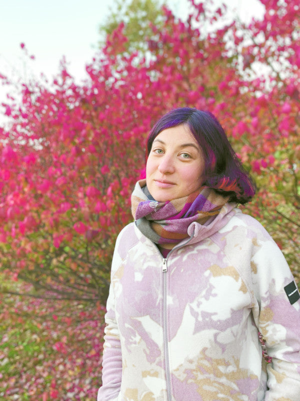 Zobie’s Kids illustrator Lidia Churakova standing outdoors in front of shrubs with red fall leaves.